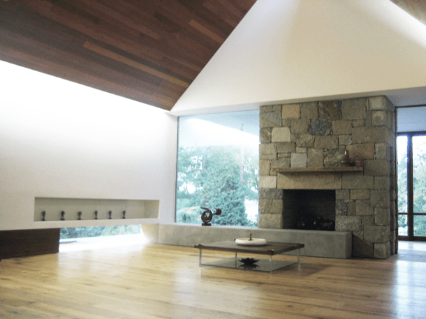 Casa de piedra, acero, y madera sala de estar con techo alto y chimenea en muro de piedra