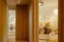 Dormitorio con pared de ladrillo pintado en blanco. Y cortina semi-rígida utilizada como puerta.