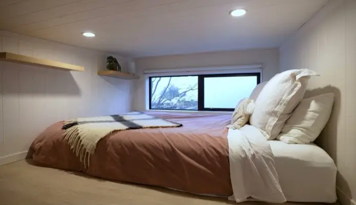 Altillo de casa mínima Wanaka, con cama grande y ventana horizontal.