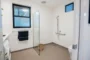 Cuarto de baño con accesorios de ayuda en váter y ducha.