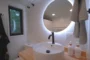 Lavabo del cuarto de baño, sobre encimera. Con espejo circular.
